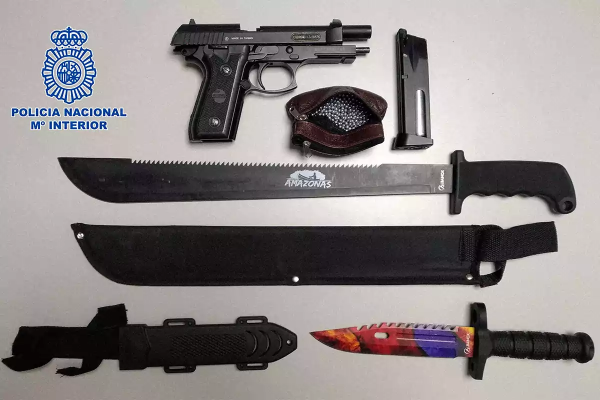 Imagen que muestra un conjunto de armas incautadas por la Policía Nacional, incluyendo una pistola, un machete y un cuchillo de colores llamativos, junto a un cargador y municiones.