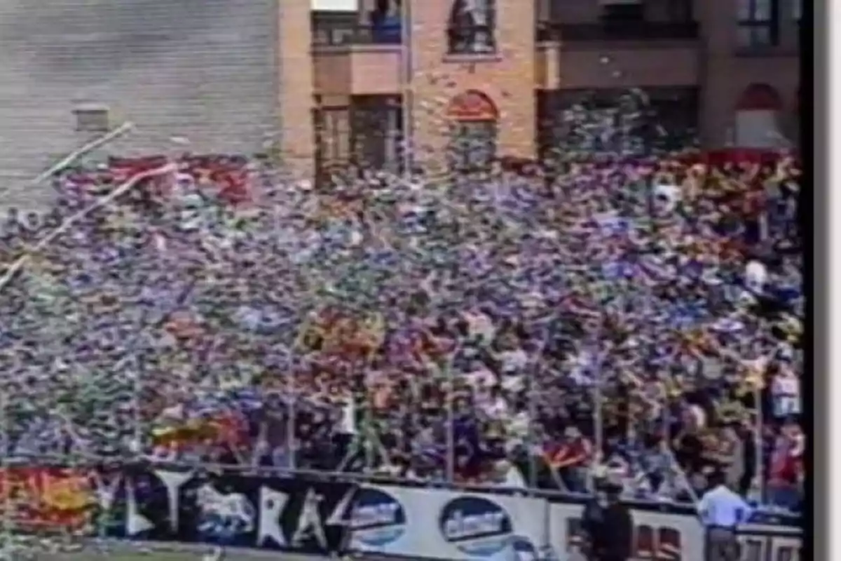 Una multitud de personas celebra en un estadio con confeti y banderas mientras un coche de policía está presente en la escena. Una multitud de personas celebra en un estadio con confeti y banderas mientras un coche de policía está presente en la escena.