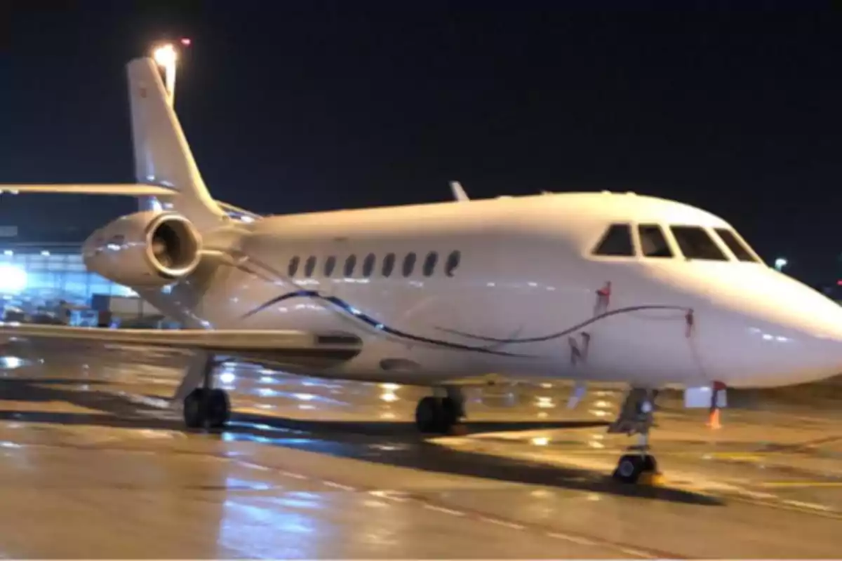 Un avión privado estacionado en una pista de aterrizaje durante la noche.