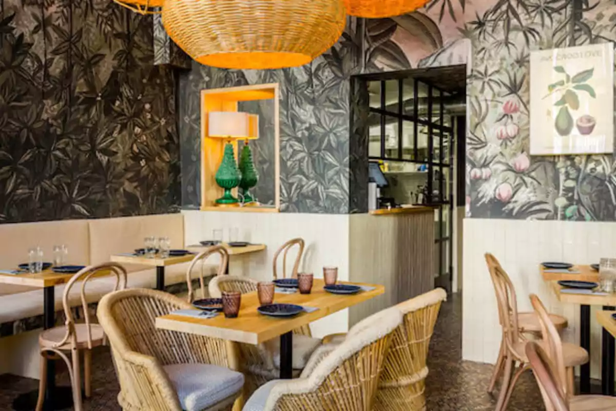 Un restaurante con decoración tropical, mesas de madera, sillas de mimbre y lámparas colgantes de mimbre.