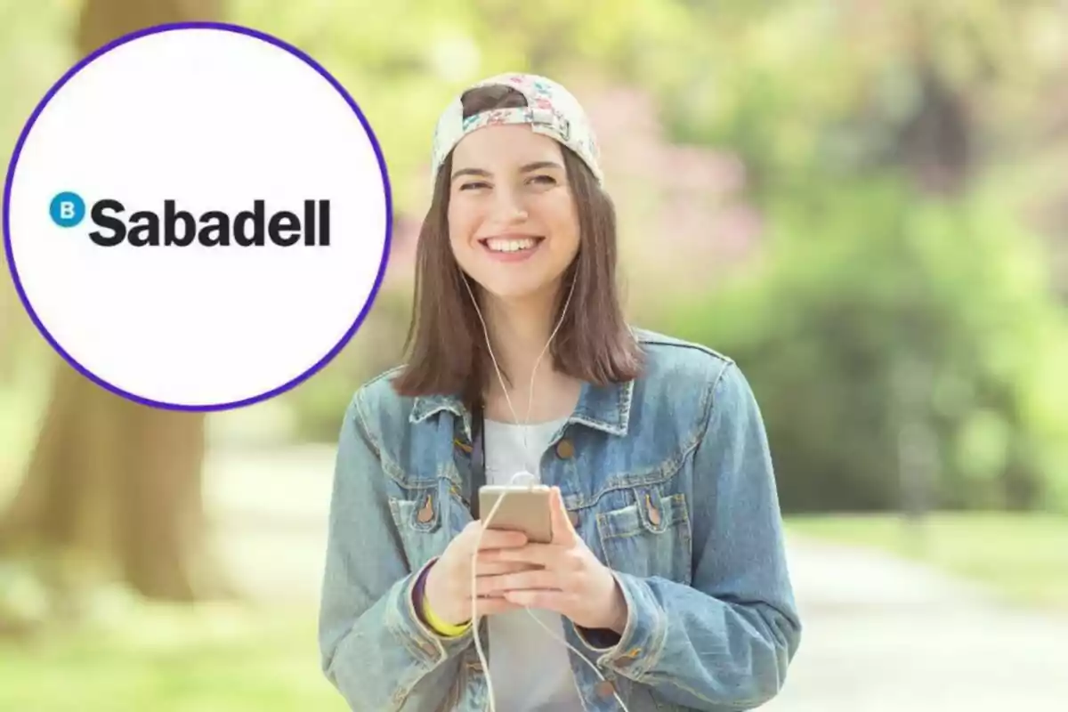 Una joven sonriente con una gorra y chaqueta de mezclilla sostiene un teléfono móvil mientras escucha música con auriculares, junto a un logotipo de Sabadell.