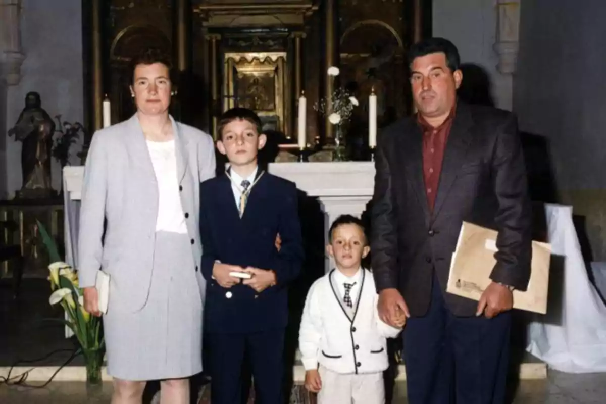 Una familia posando en un altar de iglesia con dos niños vestidos formalmente.