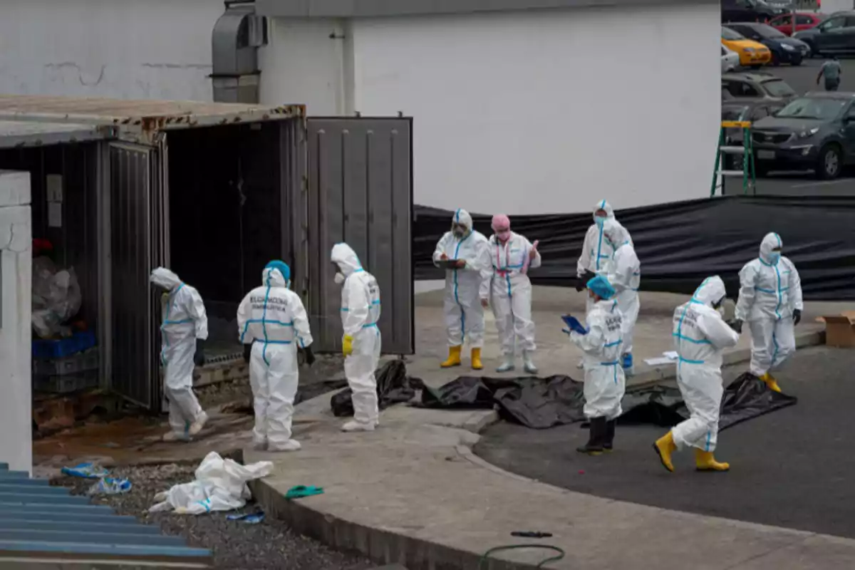Personas con trajes de protección biológica trabajando alrededor de un contenedor abierto en un área industrial.