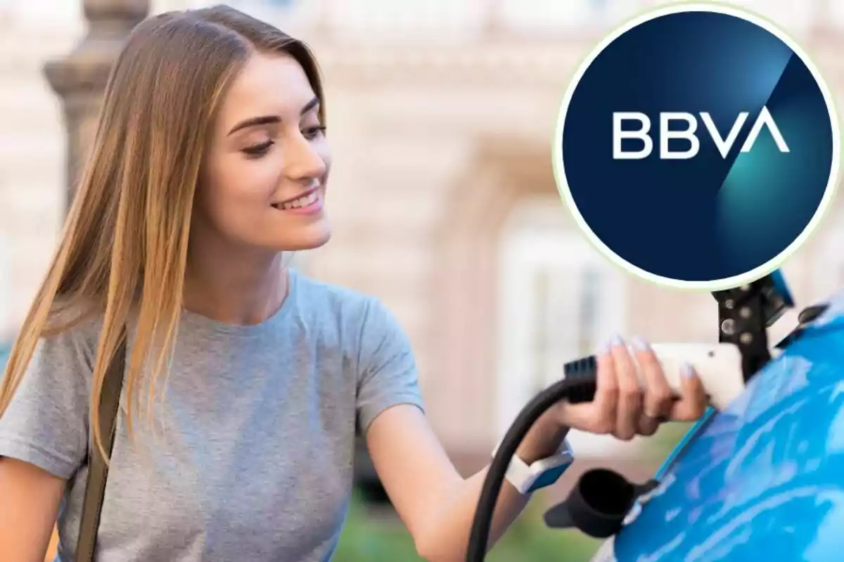 Una mujer sonriente cargando un coche eléctrico con el logotipo de BBVA en la esquina superior derecha.