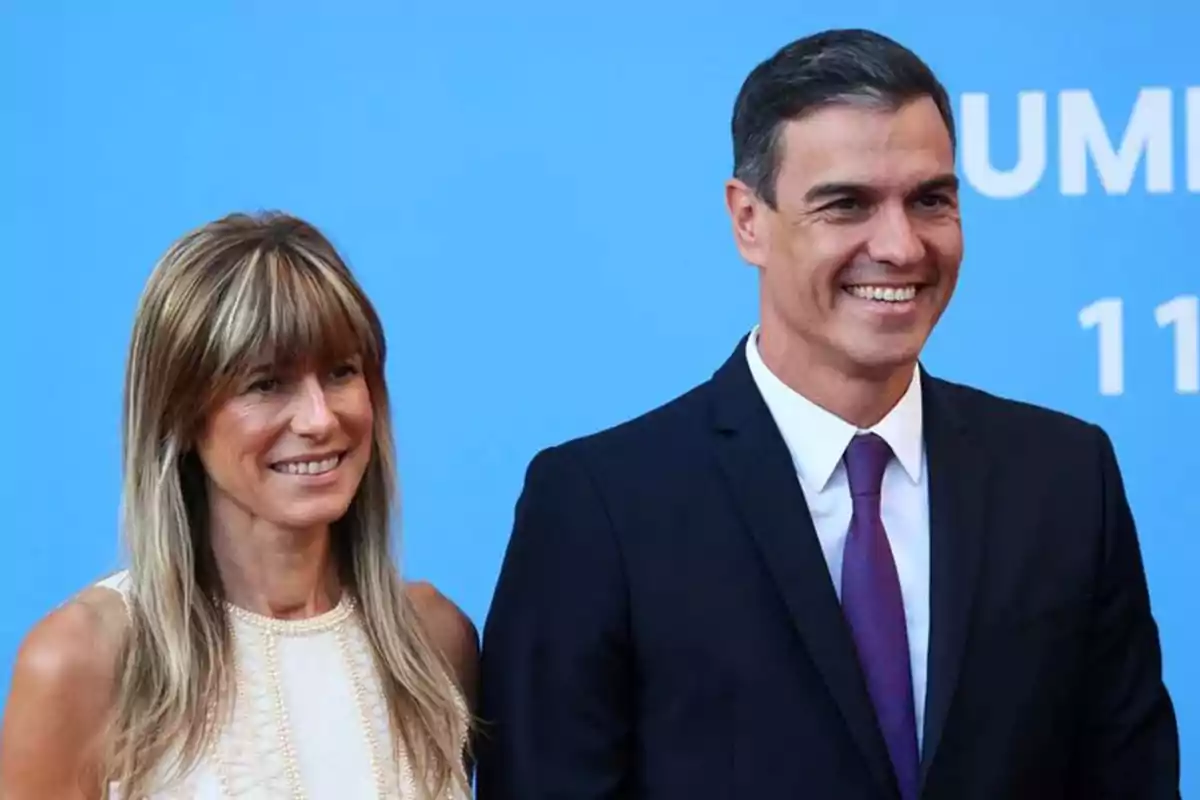 Una mujer y un hombre sonriendo frente a un fondo azul.