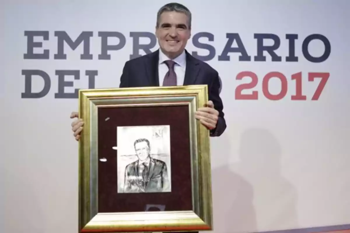 Hombre sosteniendo un cuadro en una ceremonia de premiación con el texto "EMPRESARIO DEL 2017" en el fondo.