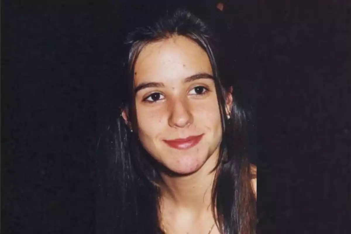 Una joven con cabello oscuro y una expresión sonriente en un fondo negro.