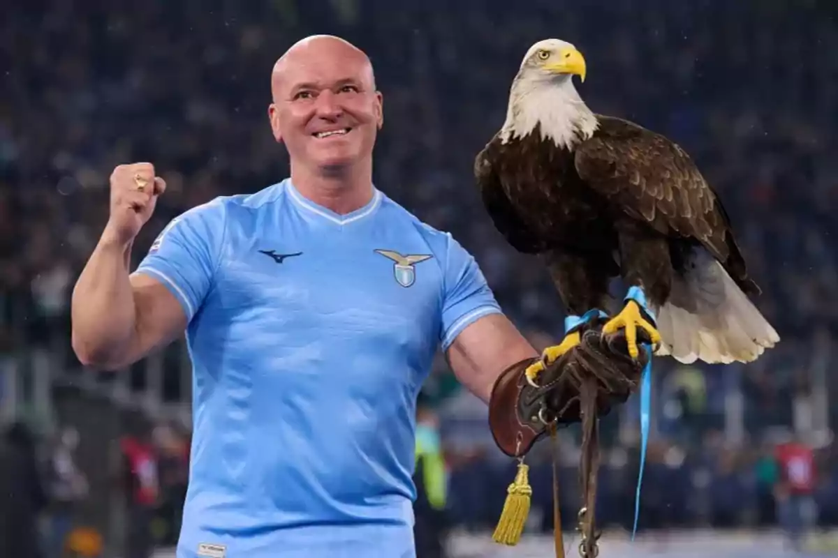 Hombre con camiseta celeste sosteniendo un águila en un estadio.