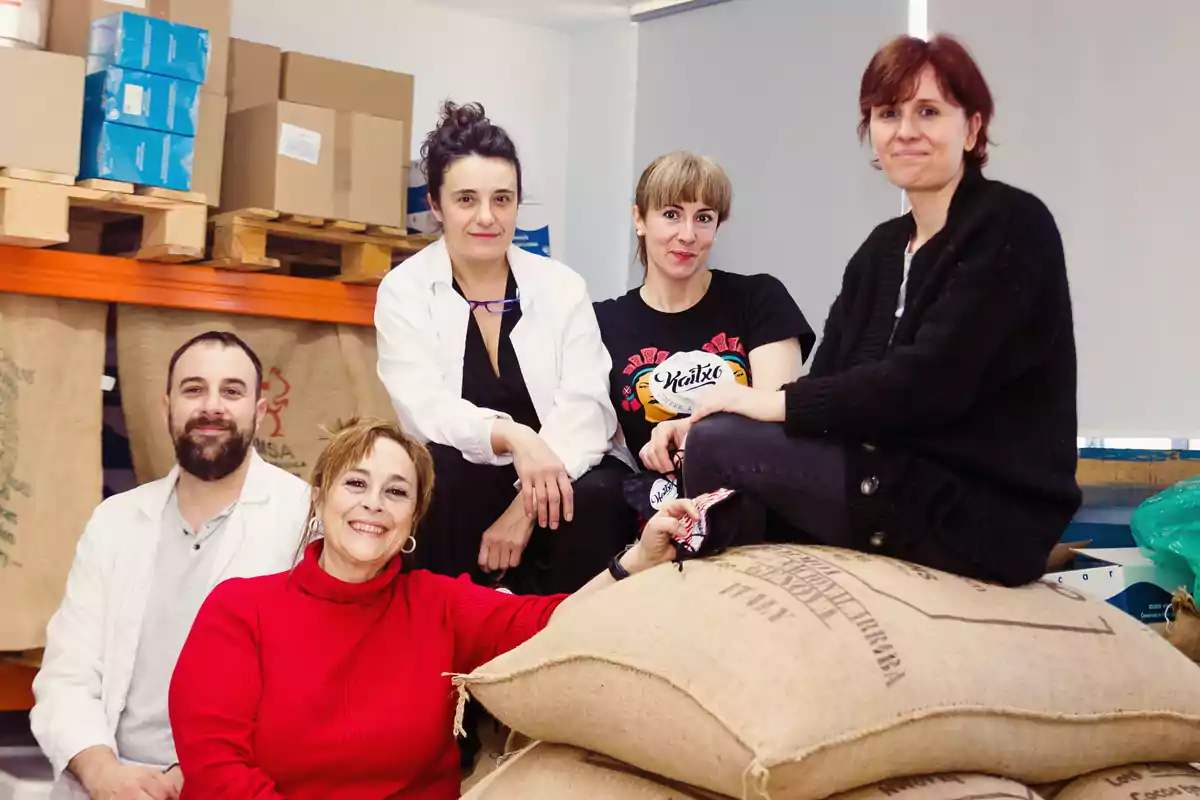 Un grupo de personas posando en un almacén con sacos de arpillera y cajas de cartón.