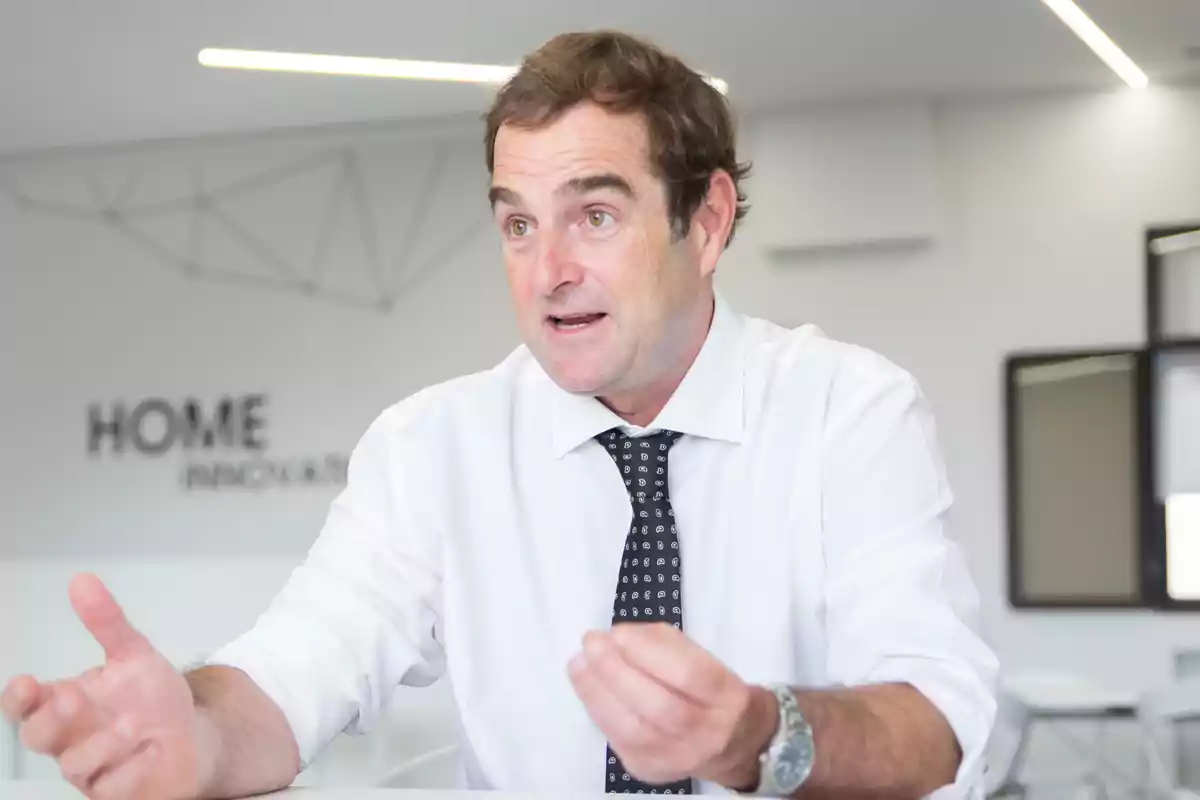 Hombre de mediana edad con camisa blanca y corbata negra gesticulando mientras habla en una oficina moderna Hombre de mediana edad con camisa blanca y corbata negra gesticulando mientras habla en una oficina moderna