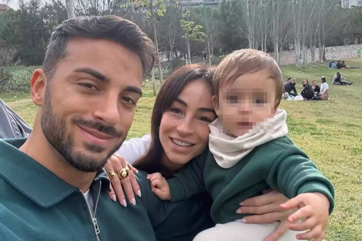 Familia sonriente tomándose una selfie en un parque con el rostro del niño pixelado Familia sonriente tomándose una selfie en un parque con el rostro del niño pixelado