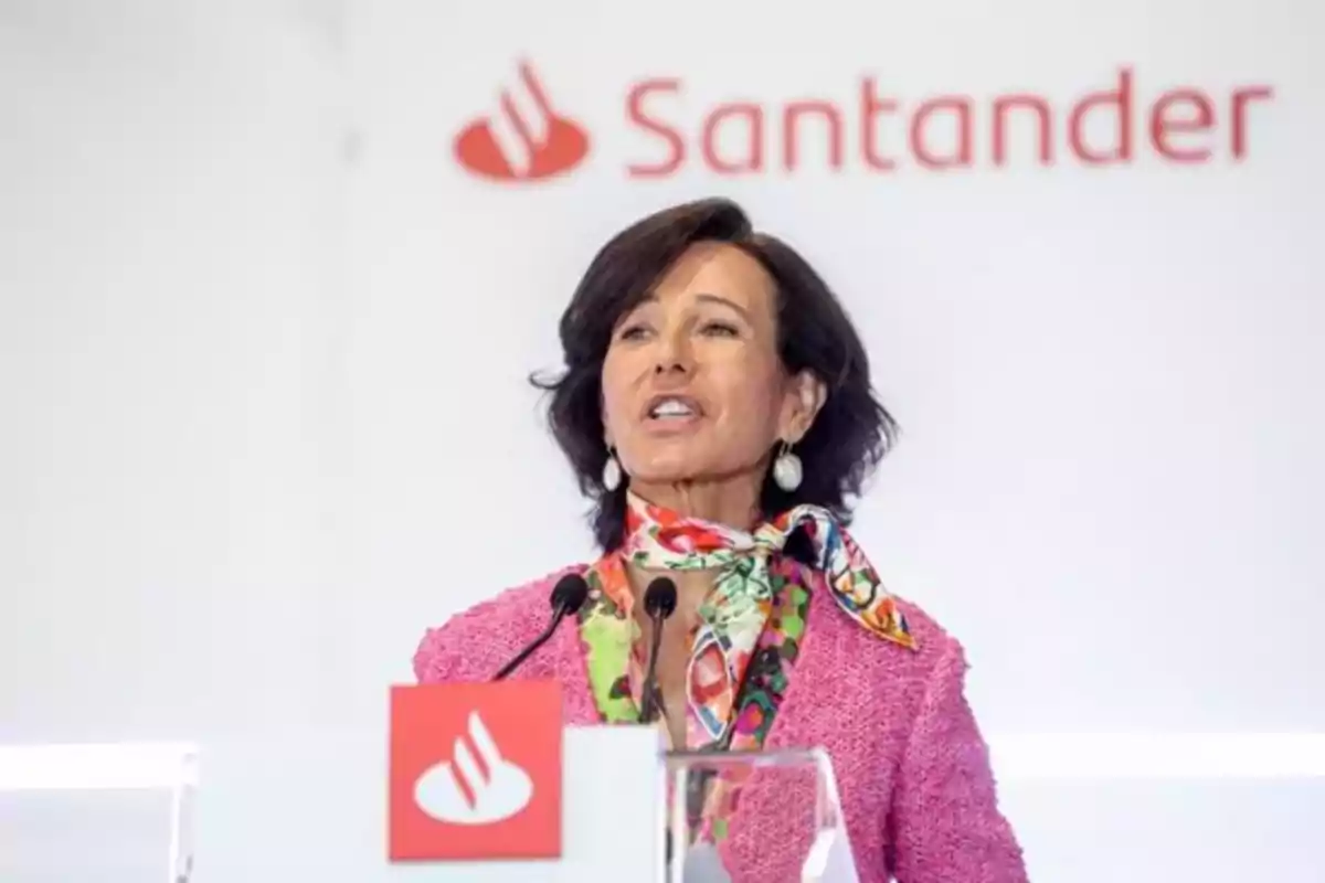 Una persona hablando en un podio con el logotipo de Santander en el fondo. Una persona hablando en un podio con el logotipo de Santander en el fondo.