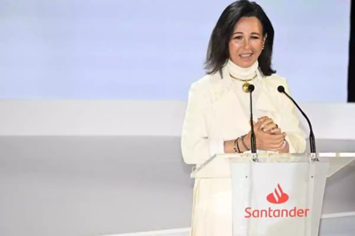 Mujer en un podio con el logotipo de Santander hablando en un evento.