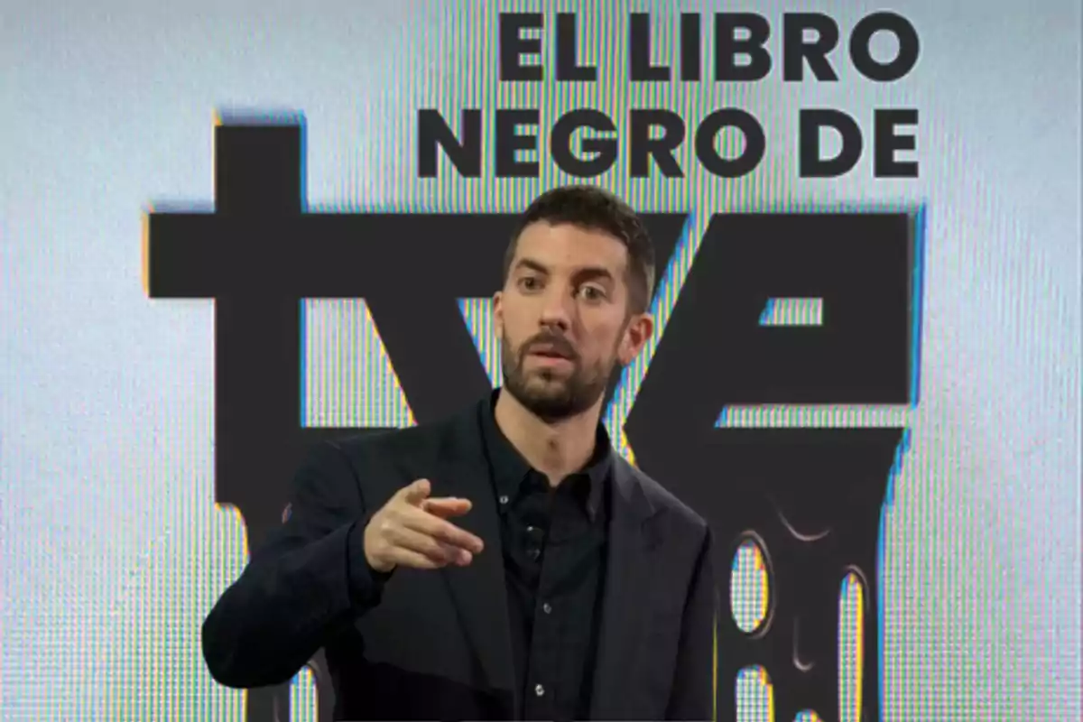 Un hombre de pie frente a un fondo que dice "El libro negro de TVE", señalando con la mano.