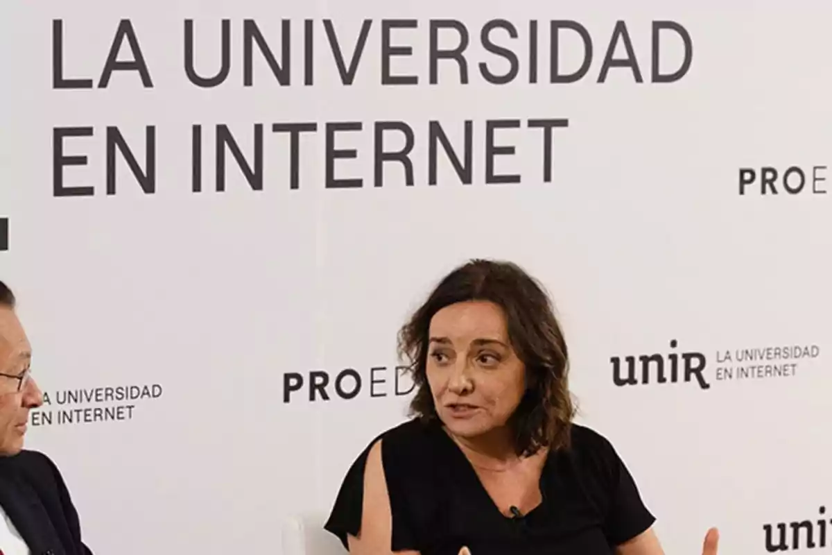 Dos personas conversando en un evento de la Universidad en Internet con un fondo que muestra el logo de UNIR.