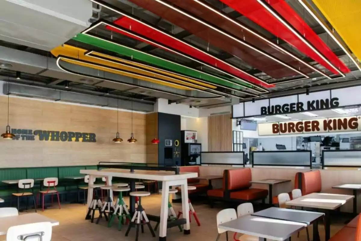 Restaurante de comida rápida Burger King con decoración moderna, techos con paneles de colores y mobiliario variado Restaurante de comida rápida Burger King con decoración moderna, techos con paneles de colores y mobiliario variado