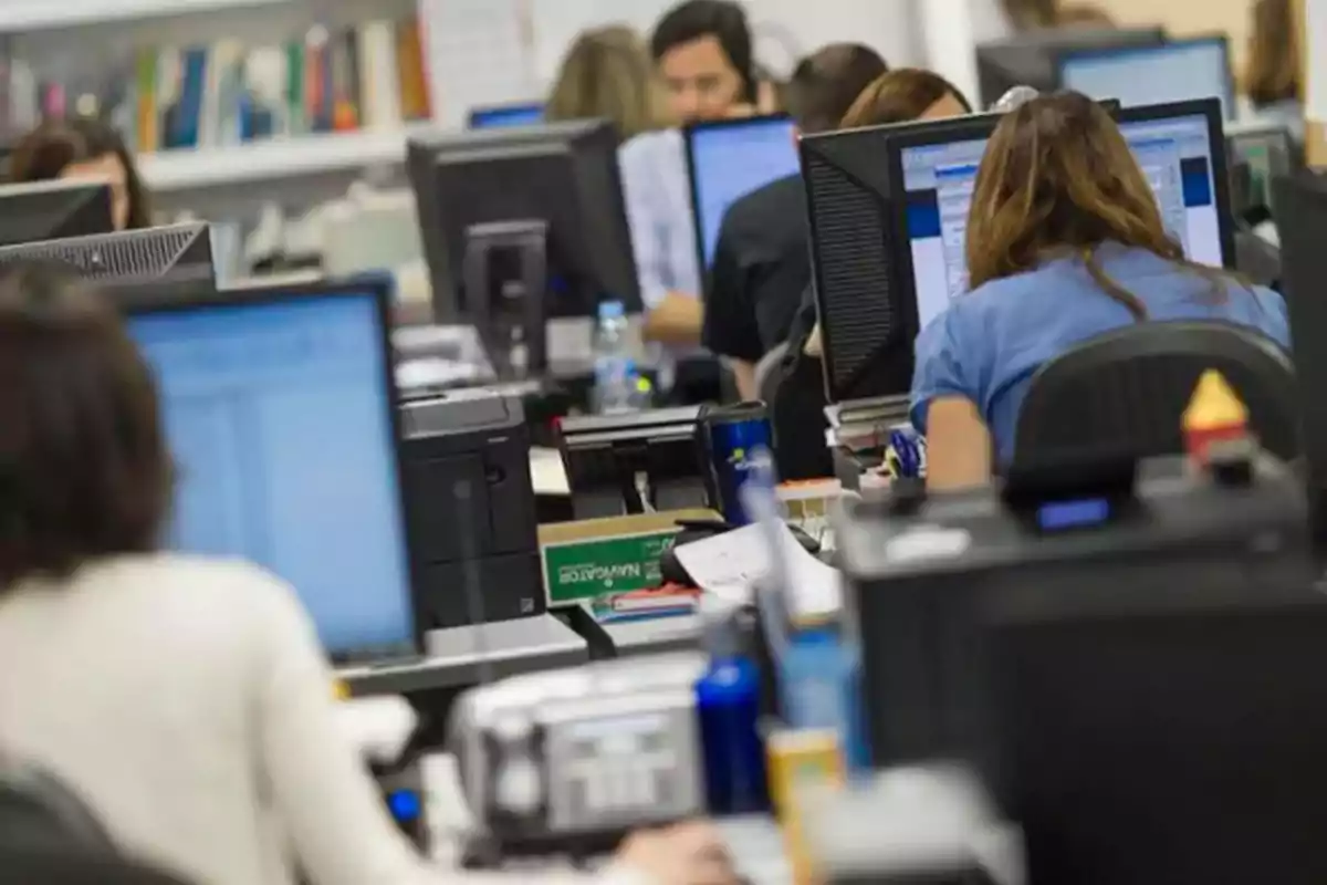 Personas trabajando en una oficina con computadoras.
