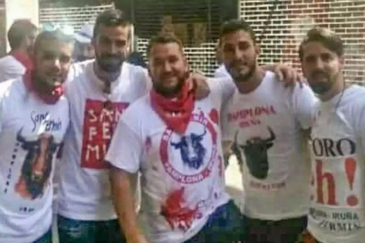 Un grupo de amigos con camisetas temáticas de toros y pañuelos rojos posan juntos durante una celebración.