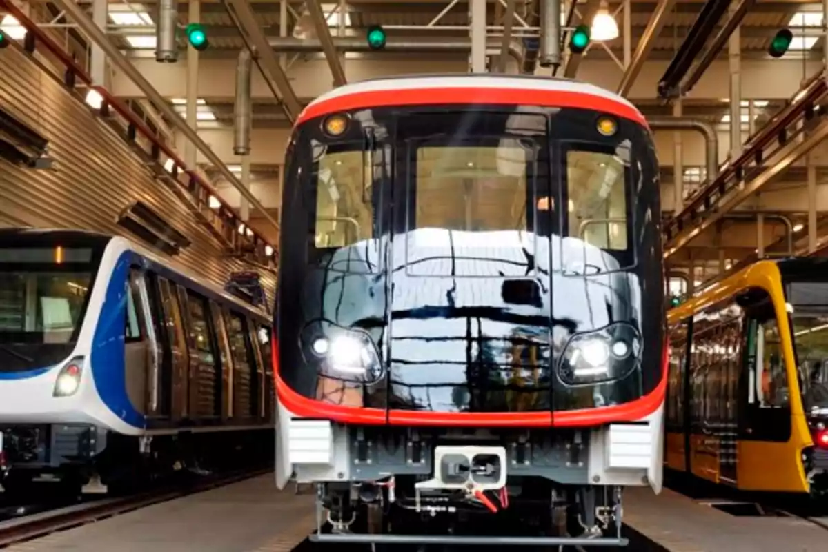 Tres trenes modernos estacionados en un taller iluminado.