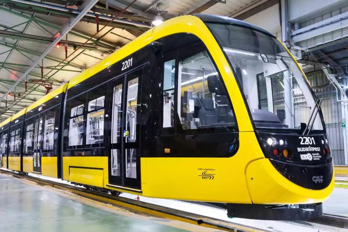 Tranvía moderno de color amarillo y negro estacionado dentro de una nave industrial Tranvía moderno de color amarillo y negro estacionado dentro de una nave industrial