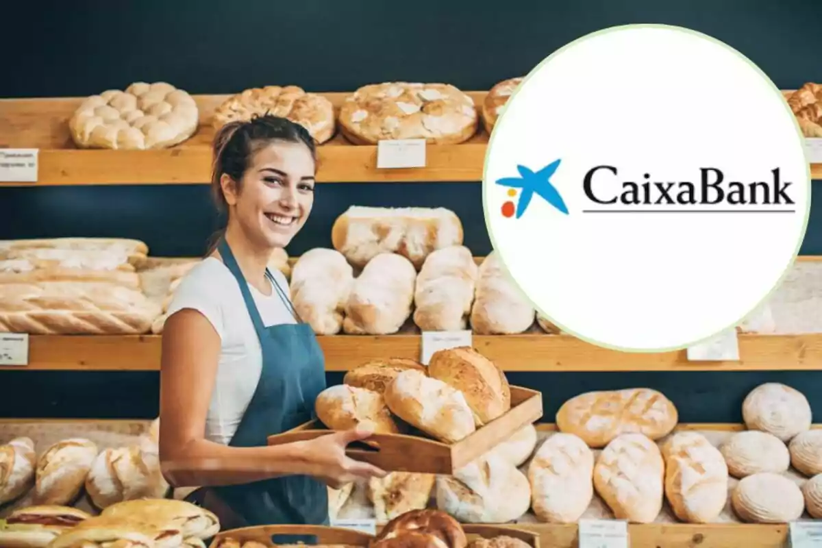 Una panadera sonriente sosteniendo una bandeja de pan en una panadería con el logotipo de CaixaBank en la esquina superior derecha.