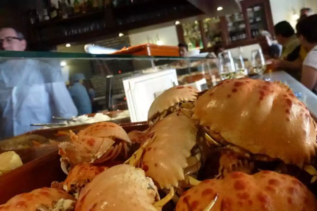 Cangrejos cocidos en un mostrador de un restaurante con personas al fondo.