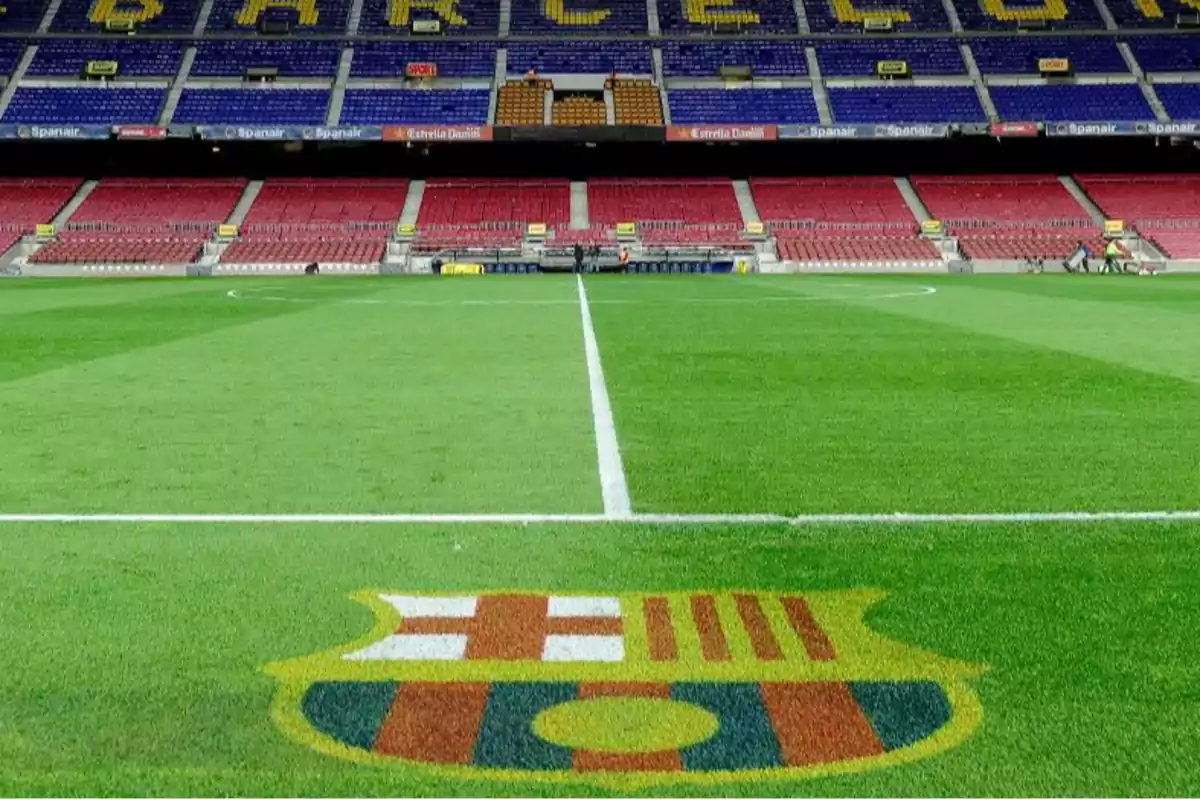 Estadio de fútbol con césped verde y gradas vacías en el fondo.