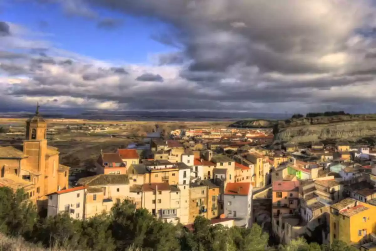 Vista panorámica de un pueblo con casas de colores y una iglesia bajo un cielo nublado.