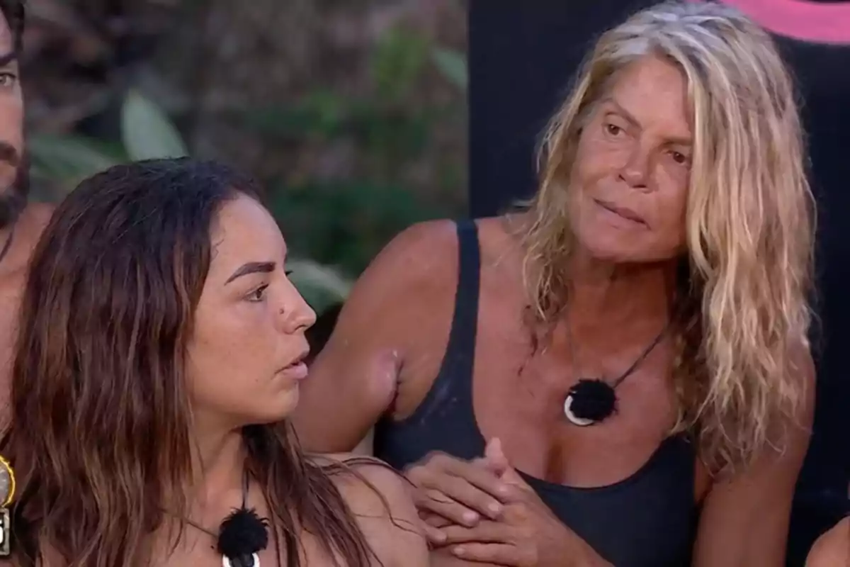 Makoke y Anita con ropa de baño oscura y collares están sentadas al aire libre Makoke y Anita con ropa de baño oscura y collares están sentadas al aire libre