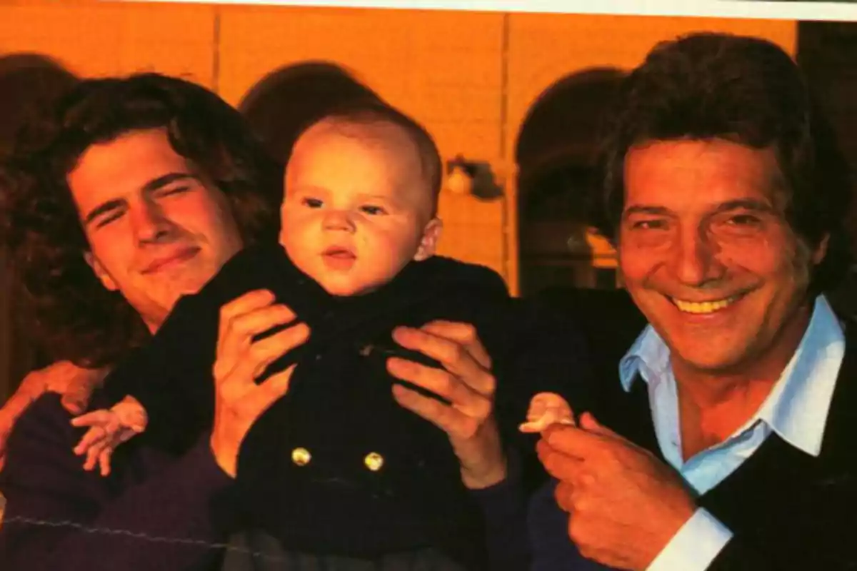 Tres personas sonrientes posando para una foto, una de ellas sosteniendo a un bebé. Tres personas sonrientes posando para una foto, una de ellas sosteniendo a un bebé.