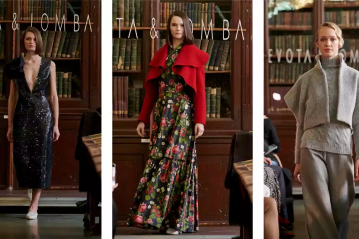 Tres modelos desfilan con diferentes atuendos en una biblioteca, una lleva un vestido negro con escote profundo, otra un vestido floral con una chaqueta roja y la tercera un conjunto gris de suéter y pantalones.