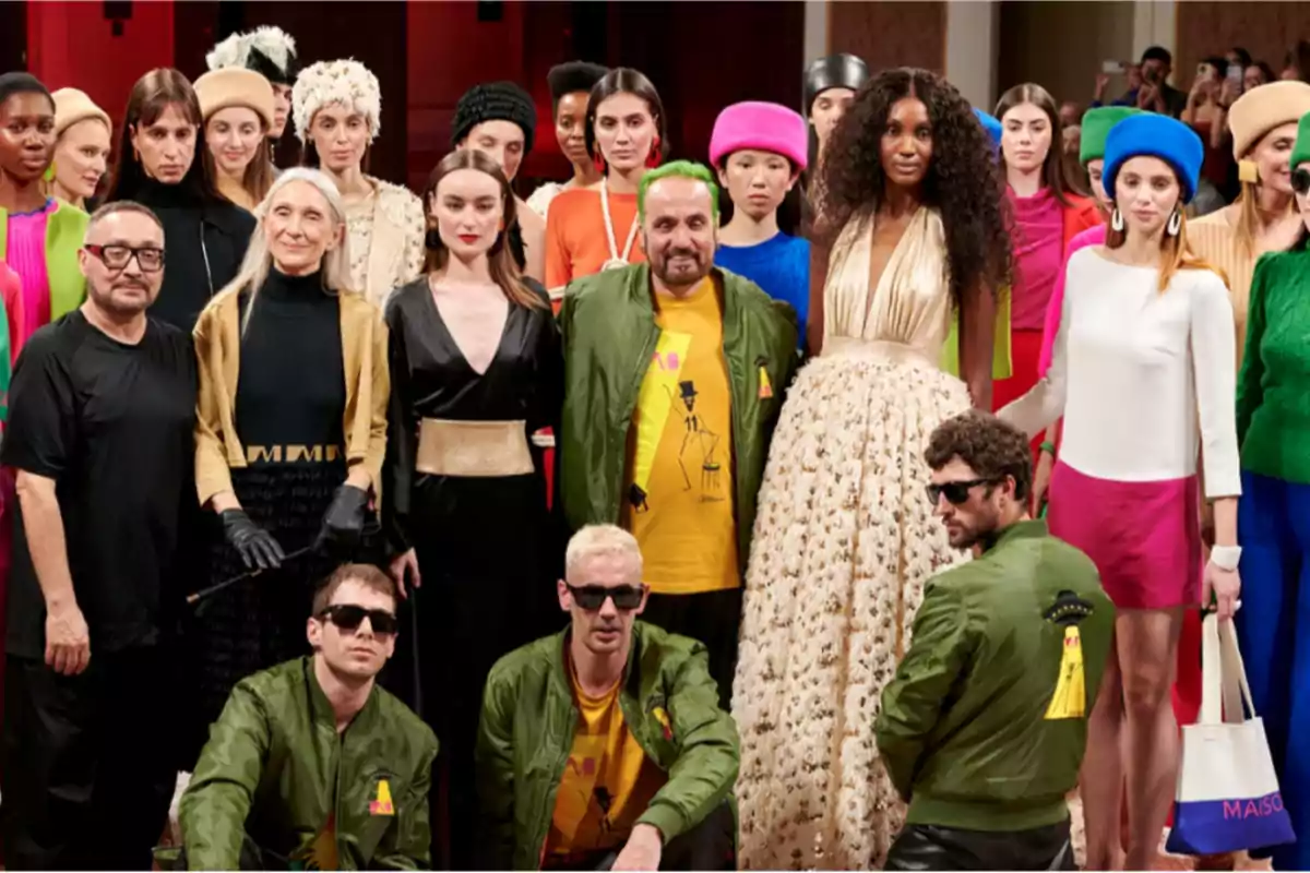 Un grupo de personas posando juntas, algunas de ellas con ropa colorida y otras con chaquetas verdes, en lo que parece ser un evento de moda.