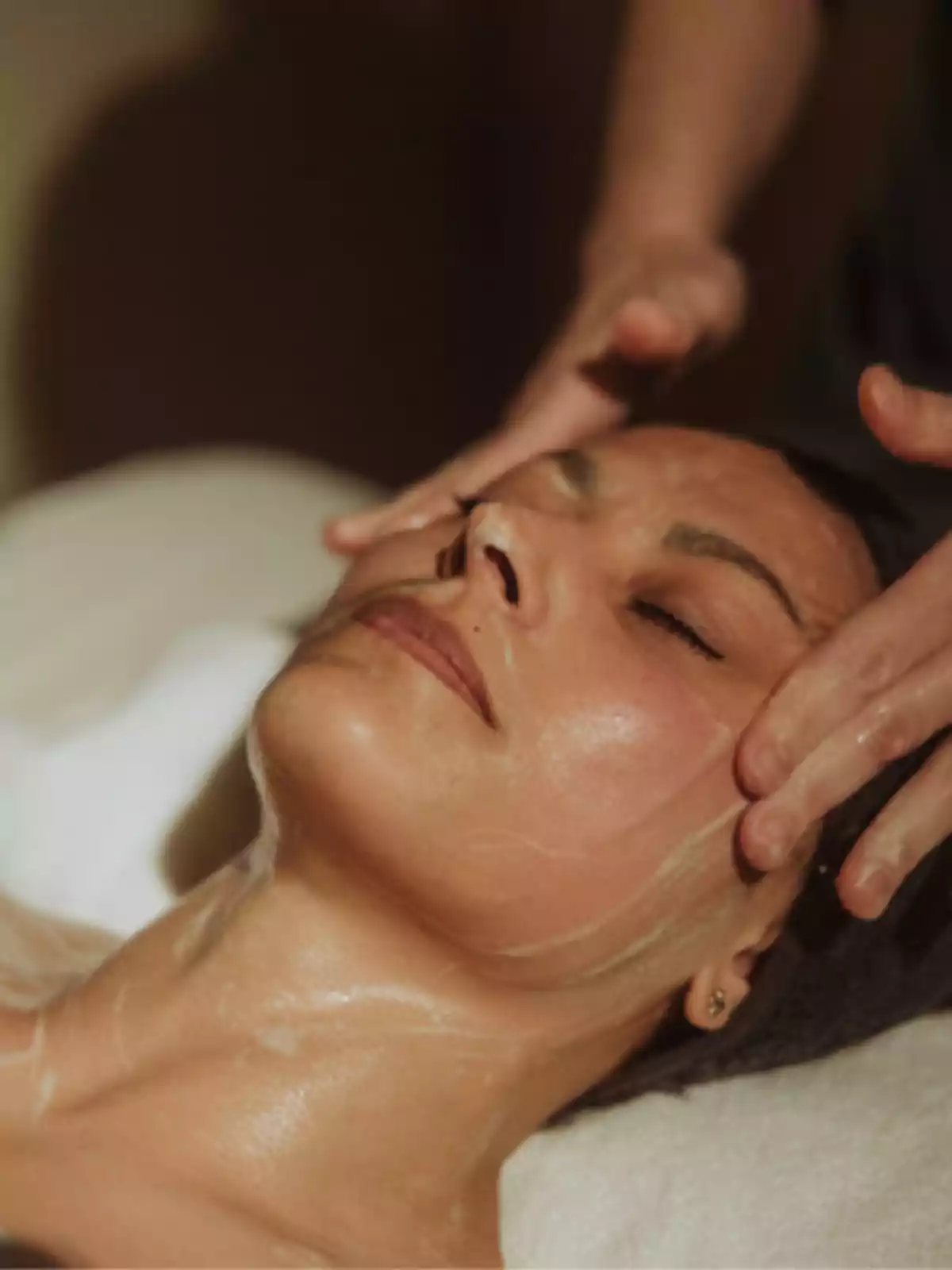Persona recibiendo un masaje facial relajante con los ojos cerrados.