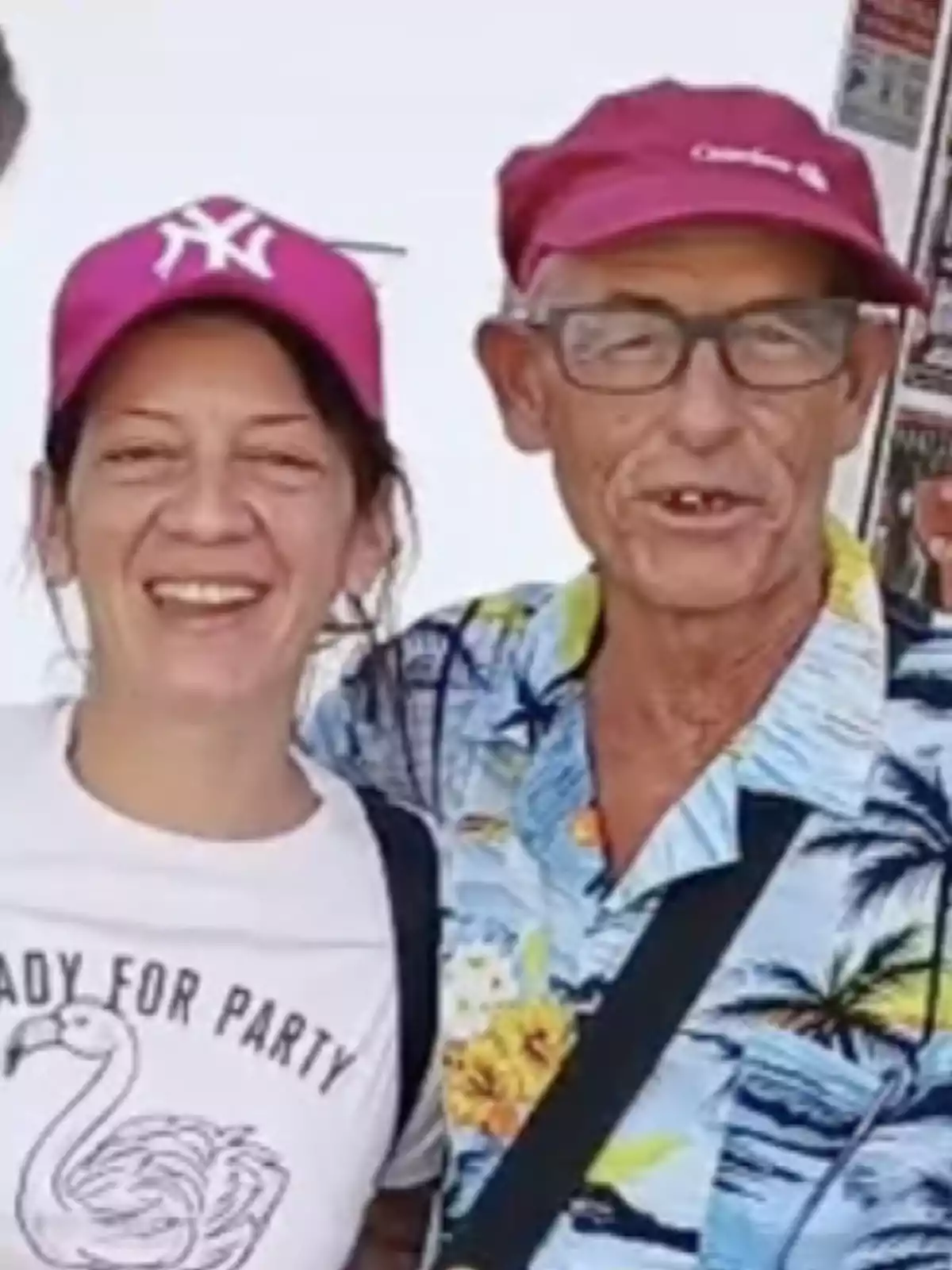 Dos personas sonrientes con gorras rosas, una con camiseta blanca y la otra con camisa hawaiana.