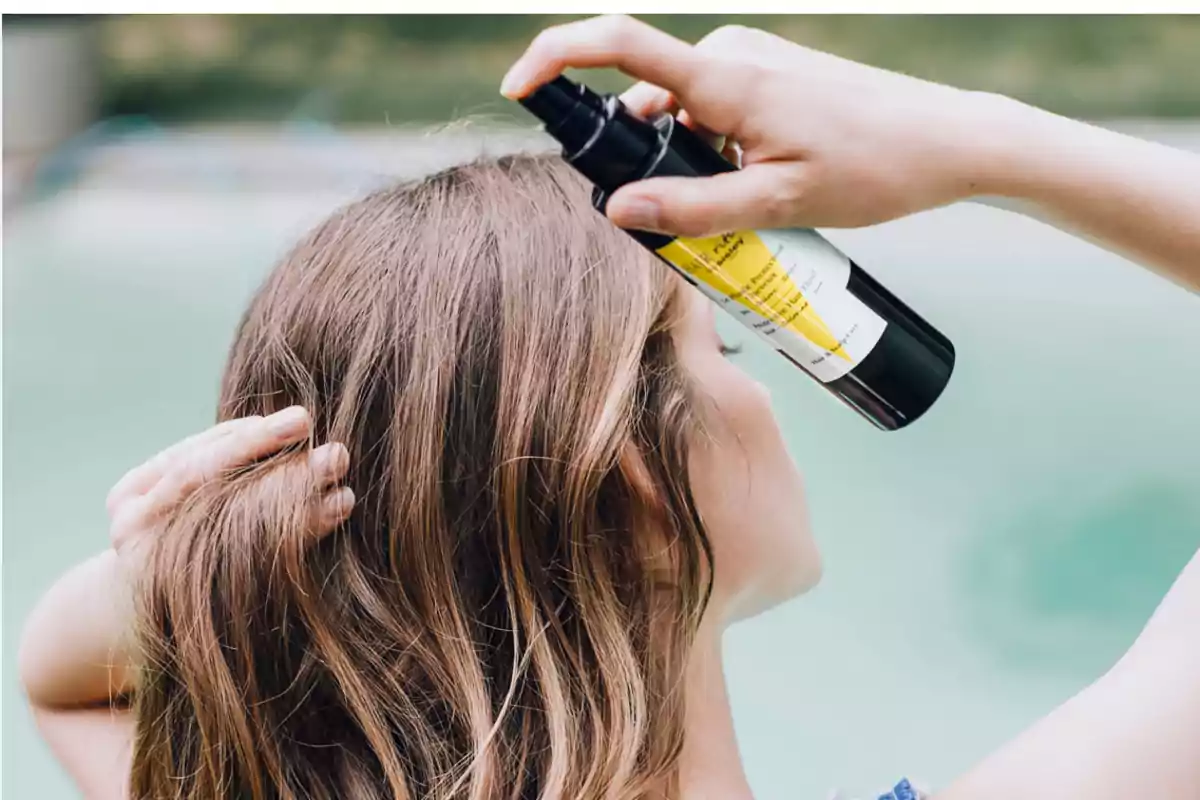 Persona aplicando spray en su cabello.