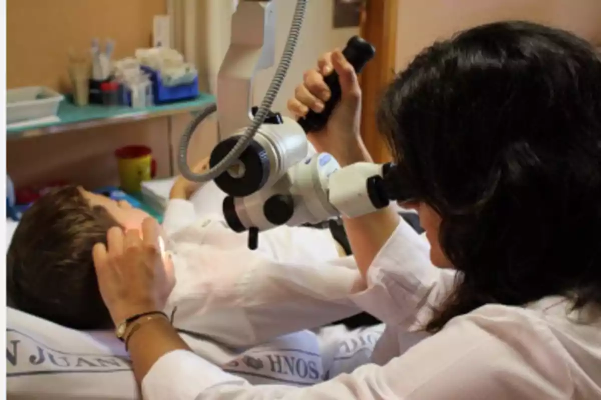 Un médico examina el oído de un niño con un otoscopio en una consulta médica.