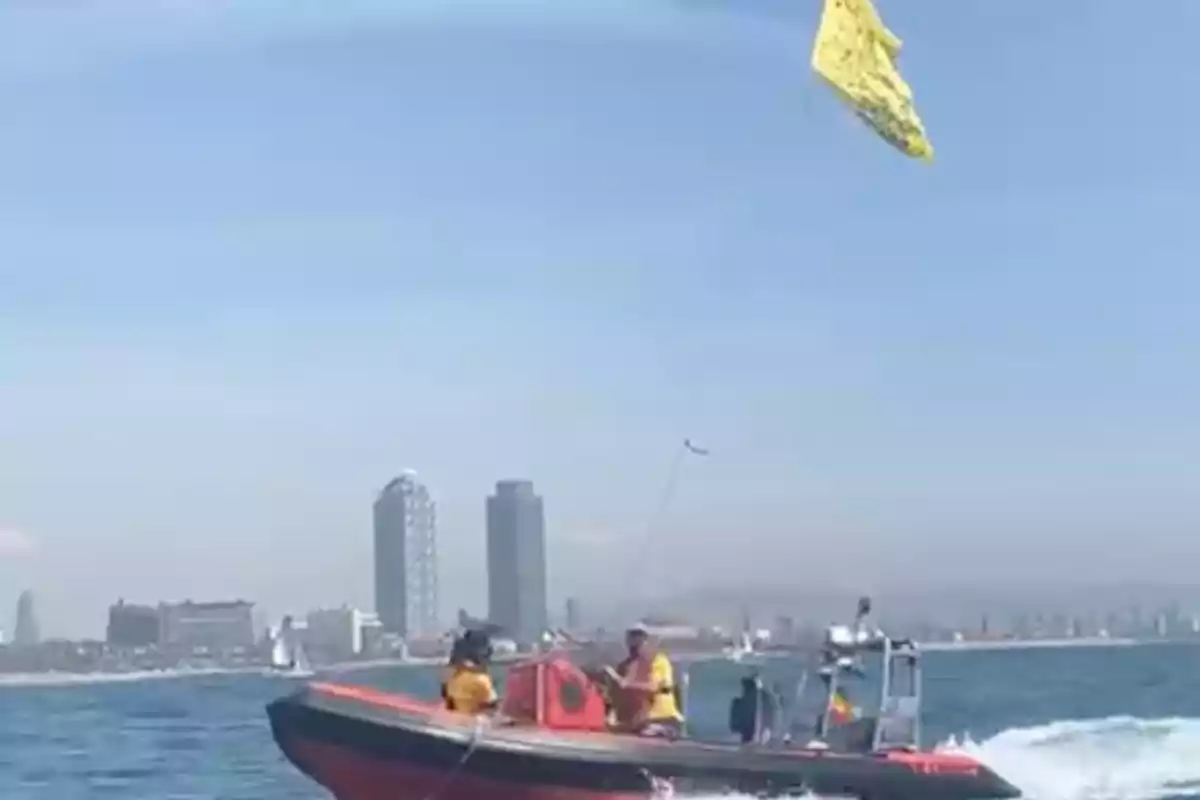 Una lancha de rescate navegando en el mar con una ciudad y edificios altos al fondo.