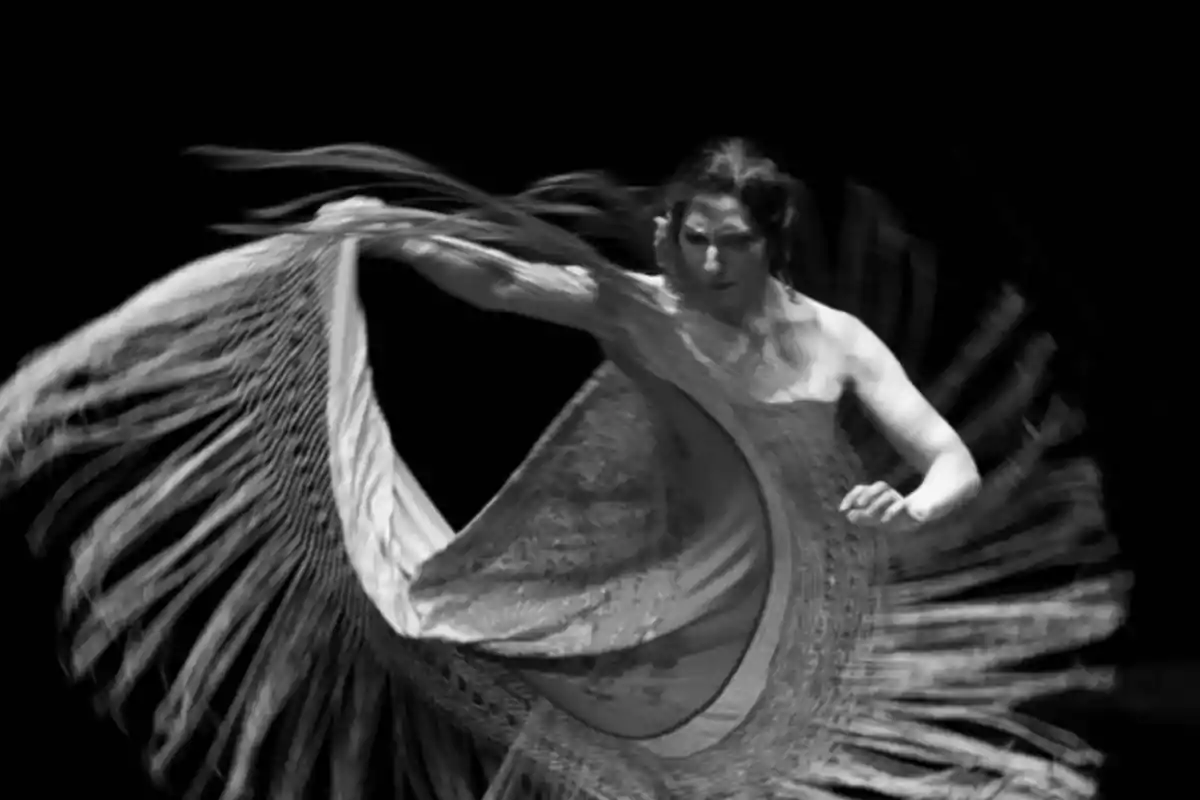 Bailarina de flamenco en movimiento con un mantón en blanco y negro.