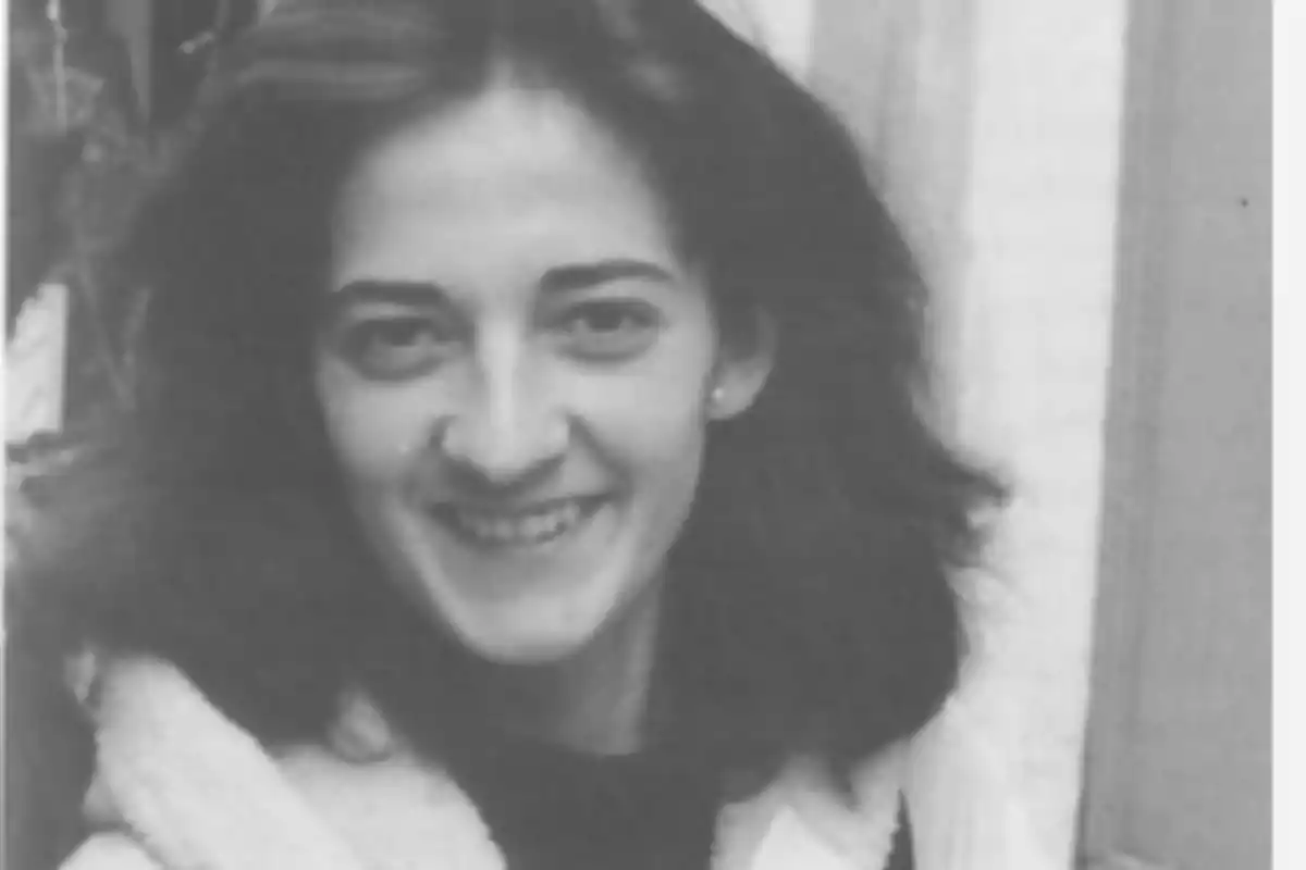 Una mujer joven con cabello oscuro y ondulado sonriendo a la cámara en una fotografía en blanco y negro.