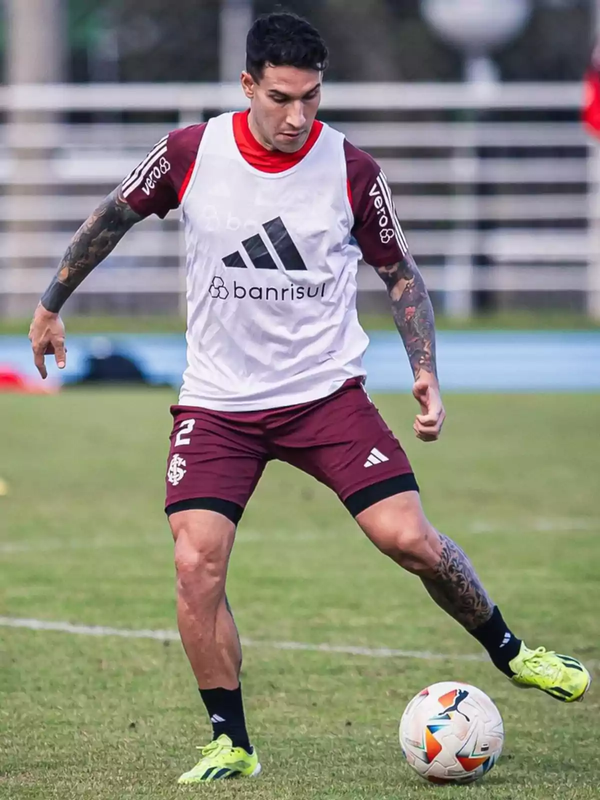 Jugador de fútbol entrenando en el campo con uniforme de entrenamiento blanco y rojo.