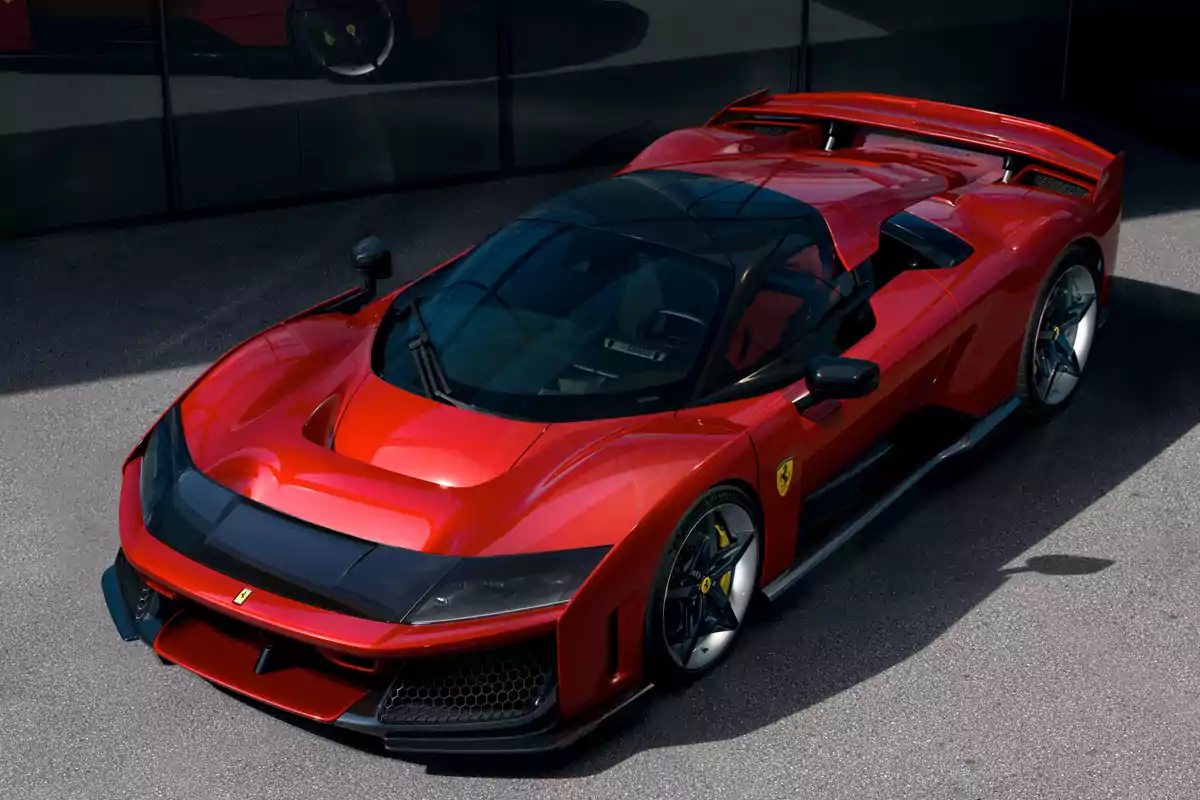 Un Ferrari F80 deportivo rojo con diseño aerodinámico y detalles en negro estacionado en una superficie pavimentada.