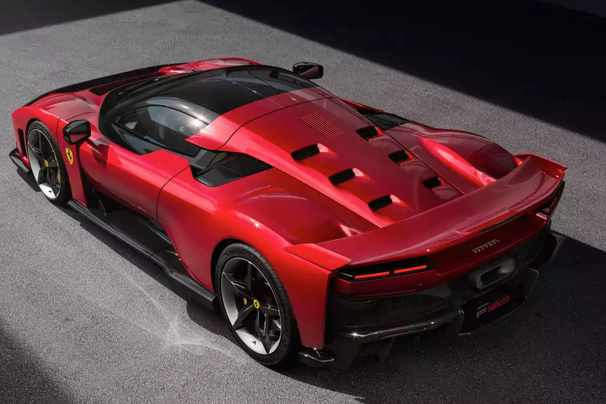 Un Ferrari F80 deportivo rojo con diseño aerodinámico y detalles en negro estacionado sobre una superficie gris.