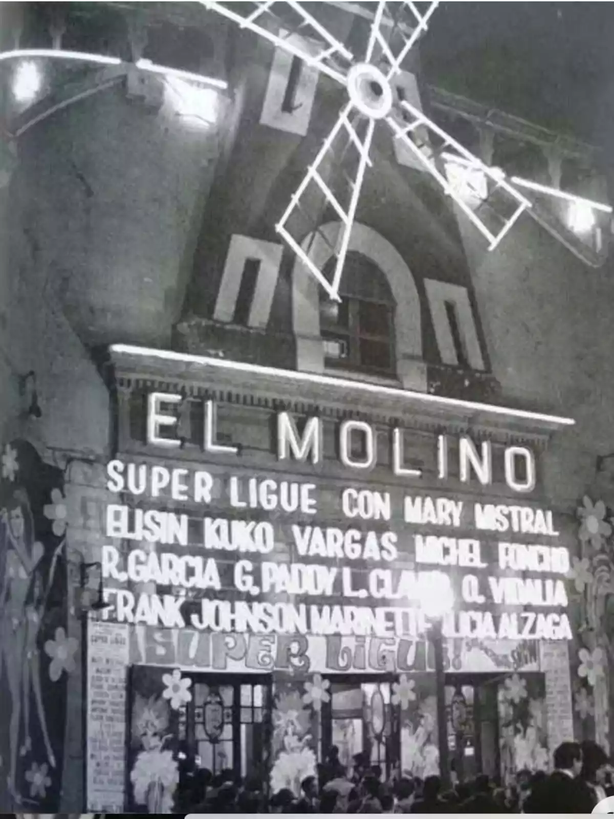 Fachada del teatro El Molino con un molino de viento iluminado y carteles anunciando un espectáculo llamado 