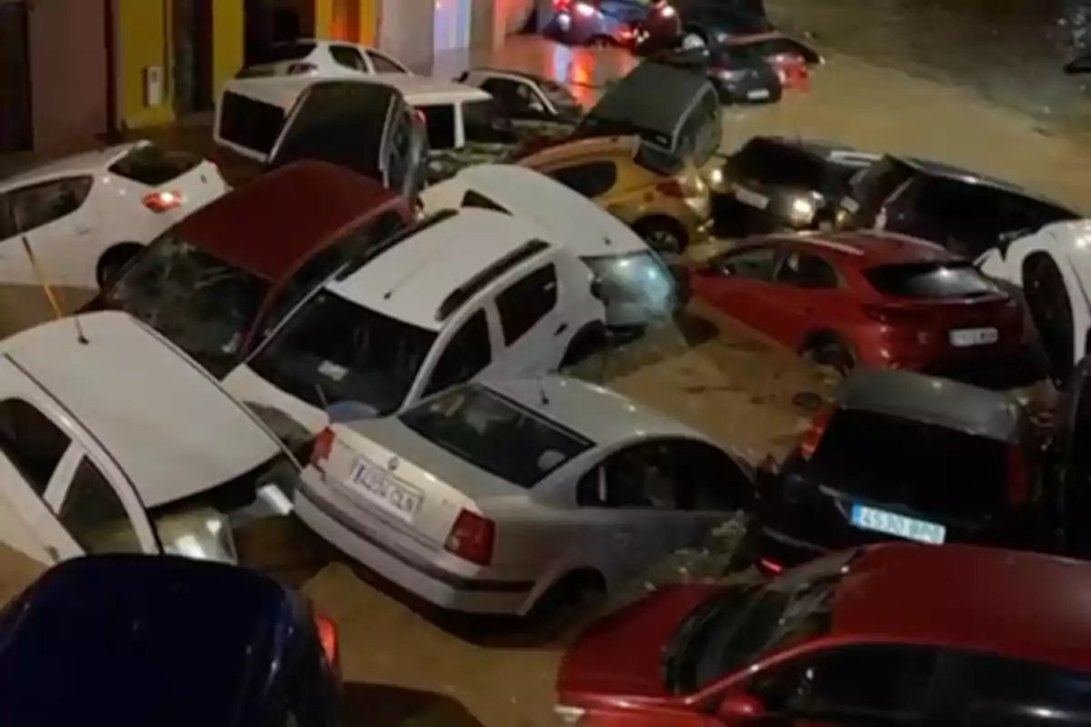 Coches amontonados y parcialmente sumergidos en una calle inundada durante la noche.