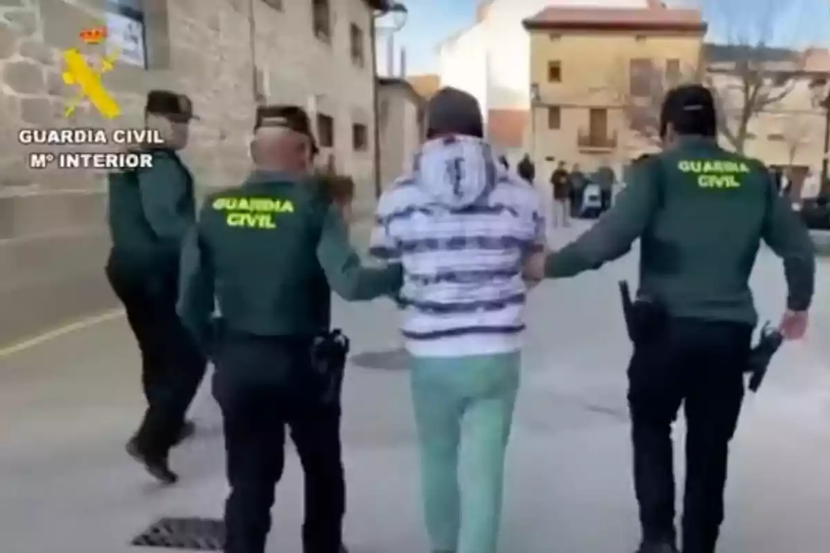 Un hombre es escoltado por dos agentes de la Guardia Civil en una calle.