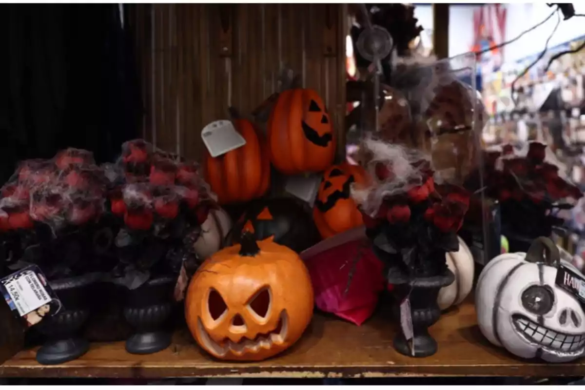 Decoraciones de Halloween con calabazas talladas y flores negras con telarañas en una estantería.