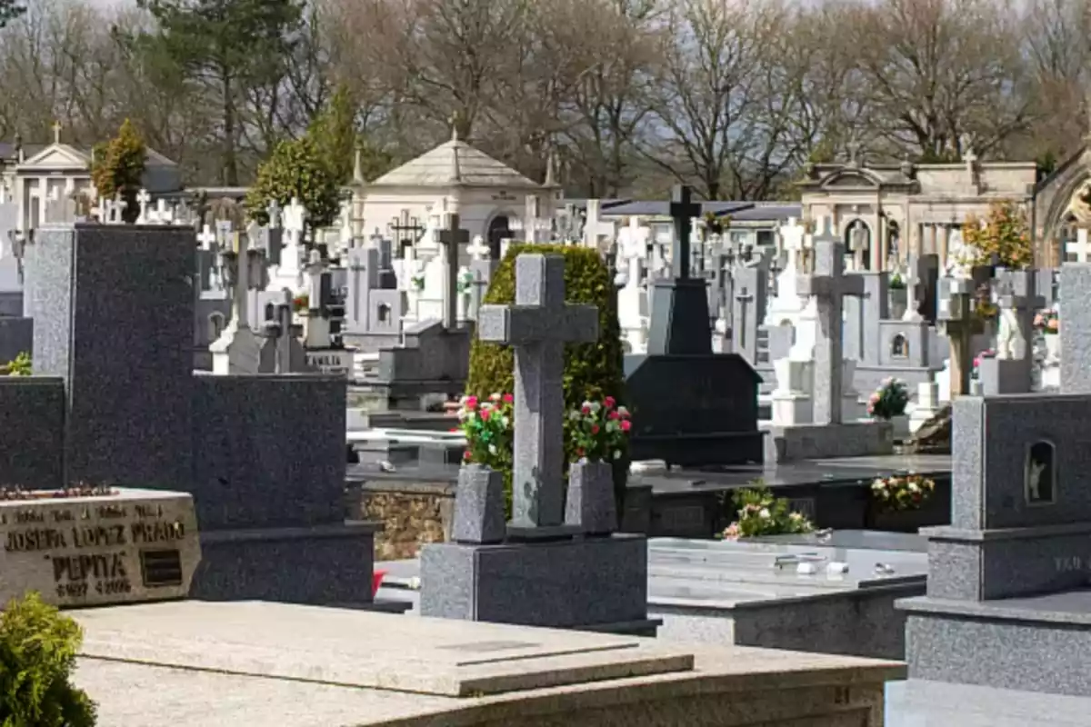 Un cementerio con varias lápidas y cruces rodeadas de árboles.