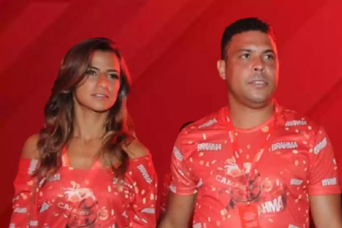 Dos personas con camisetas rojas de Brahma en un evento con fondo rojo.