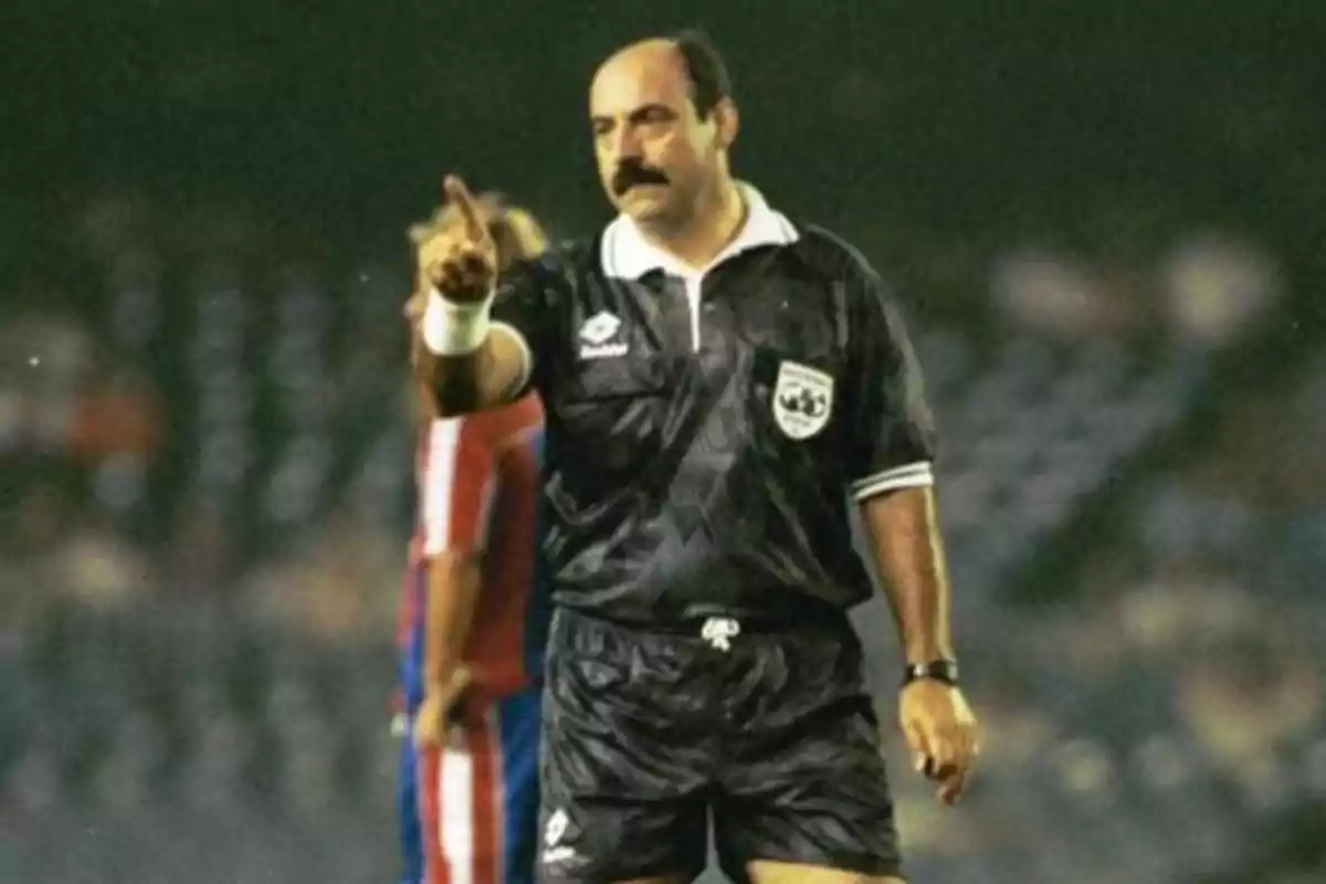 Un árbitro de fútbol en el campo señalando con el dedo durante un partido.