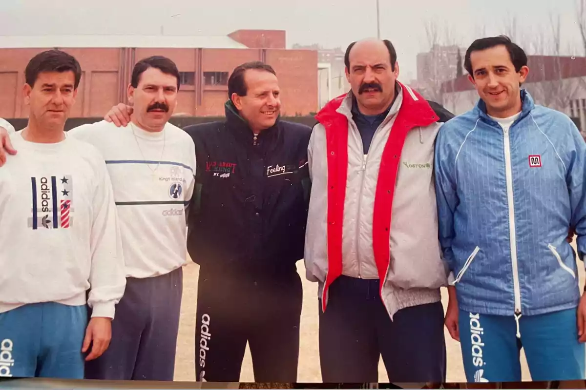 Cinco hombres posan juntos al aire libre, vistiendo ropa deportiva de diferentes marcas.